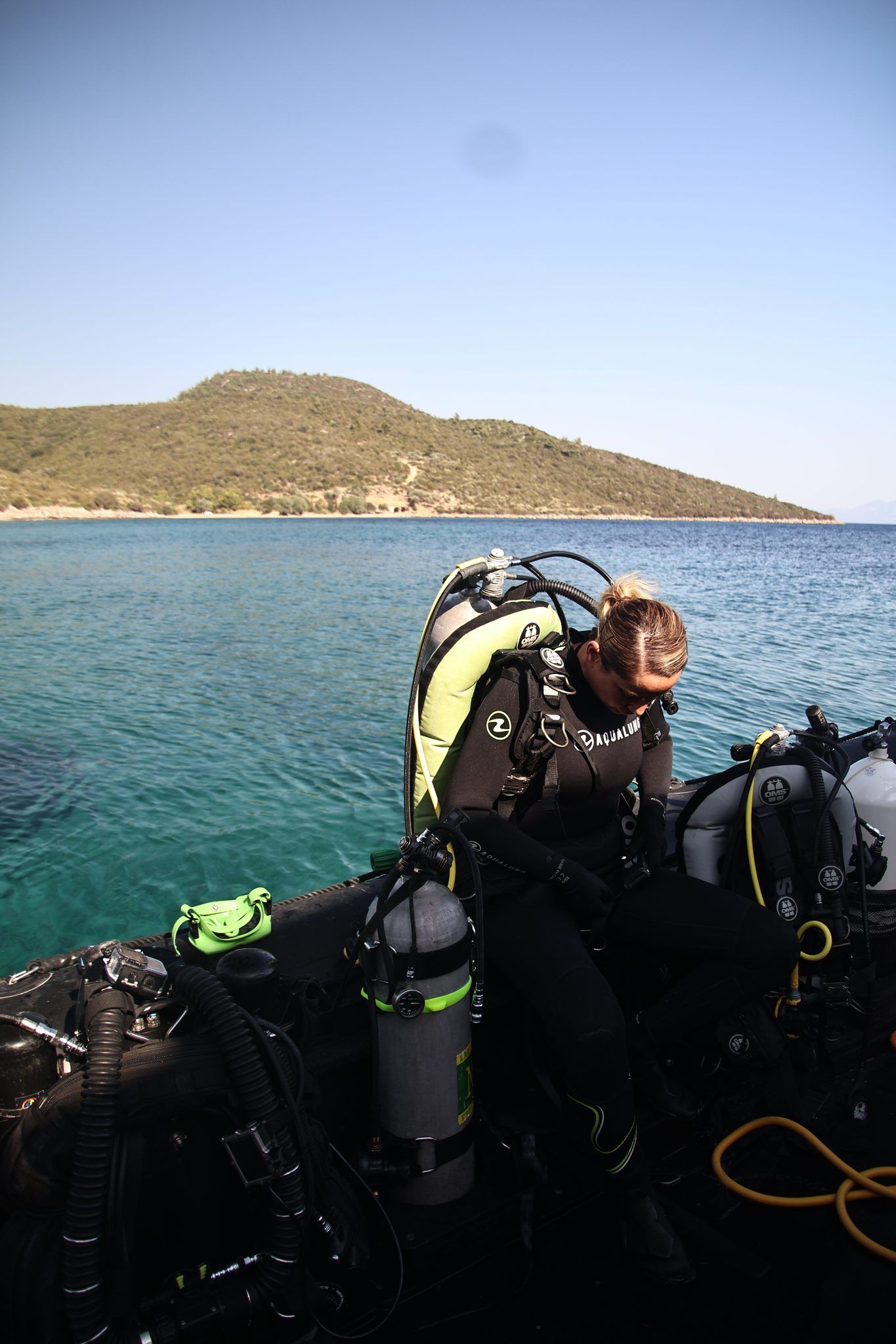 A diver gearing up on the RIB, another swimming in the bay behind