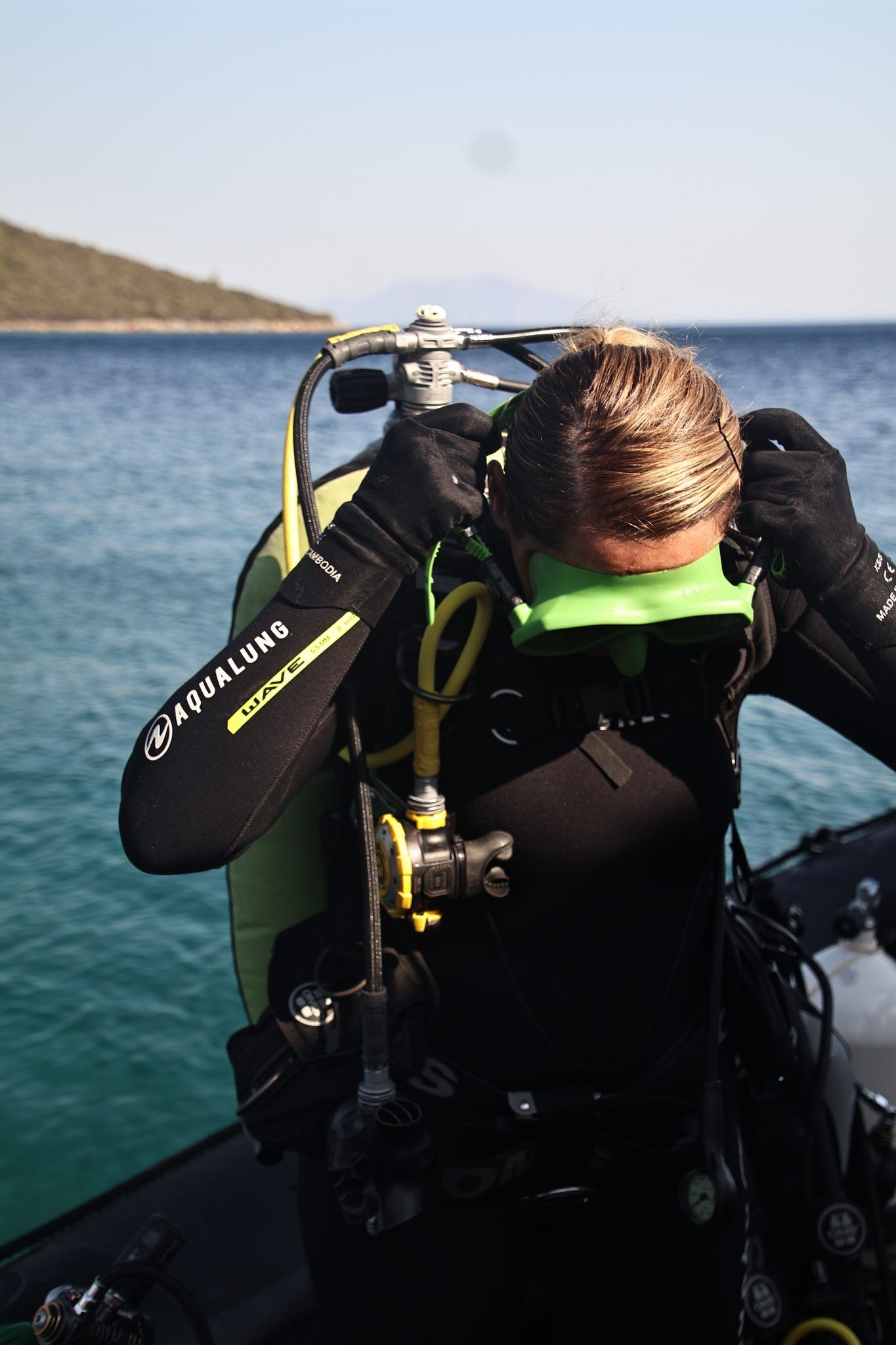 A diver seating her mask before the dive, tanks lined up around her