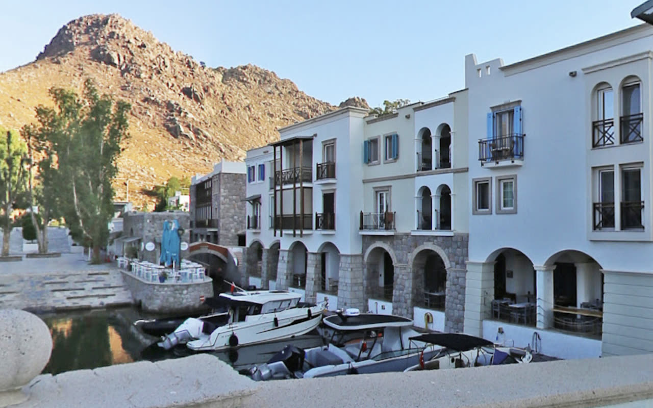 The Anthaven marina waterfront at Aspat, Bodrum: a row of stone arches along the quay with boats moored in front of them, the bare hill rising behind. DiveTalia is behind one of these arches.
