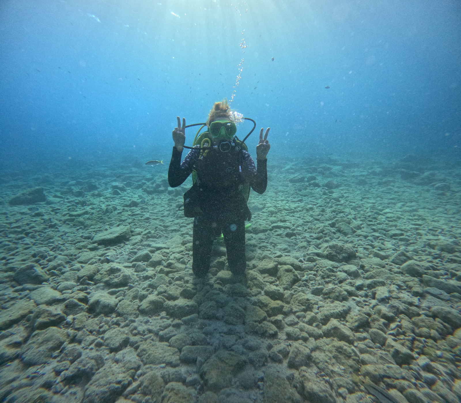 Instructor demonstrating gear to a student underwater