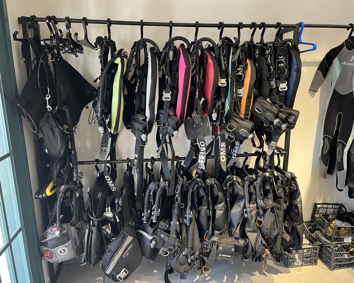 Wings and BCDs racked along the equipment room wall