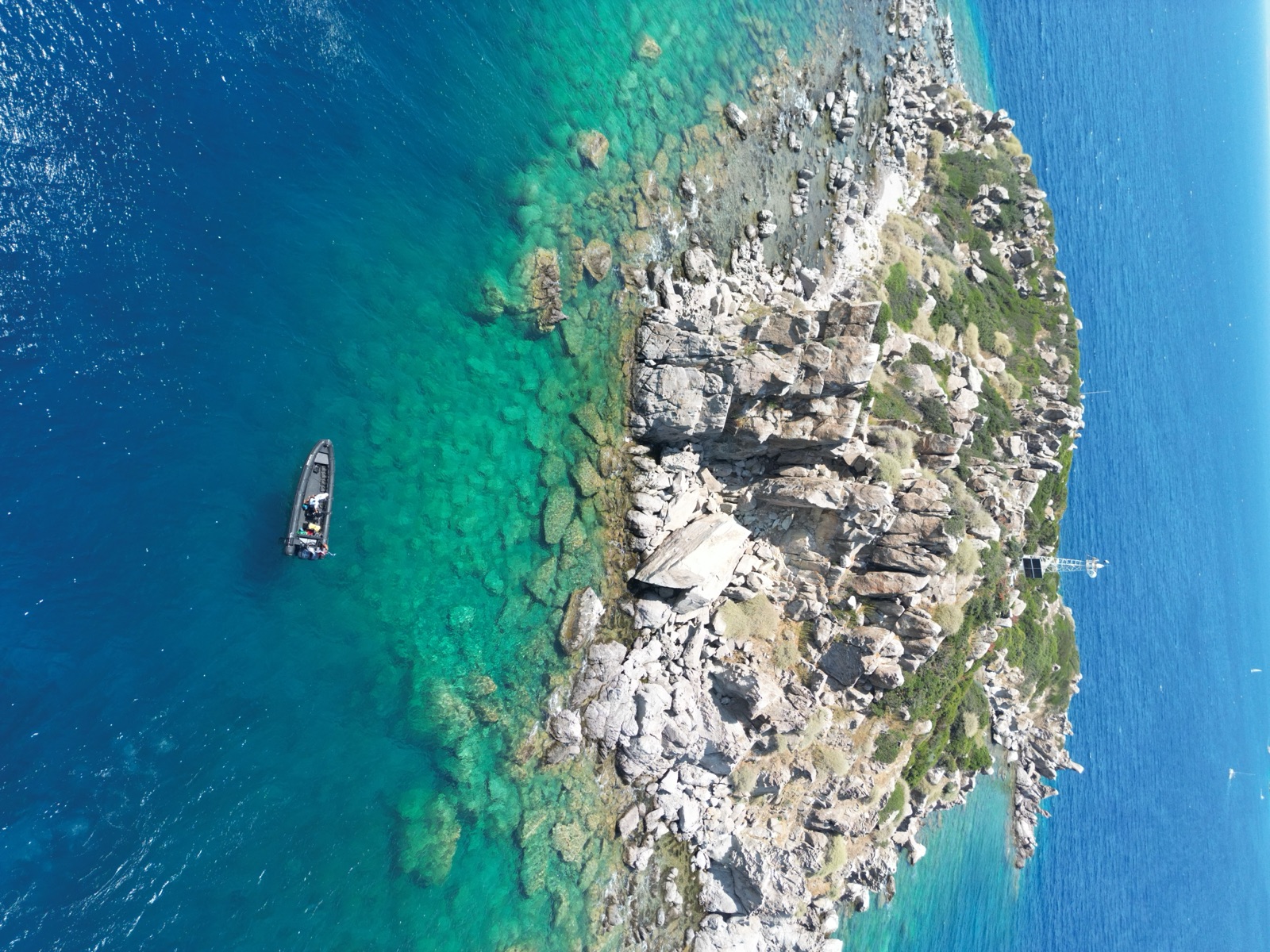The DiveTalia RIB anchored off a rocky island in clear water
