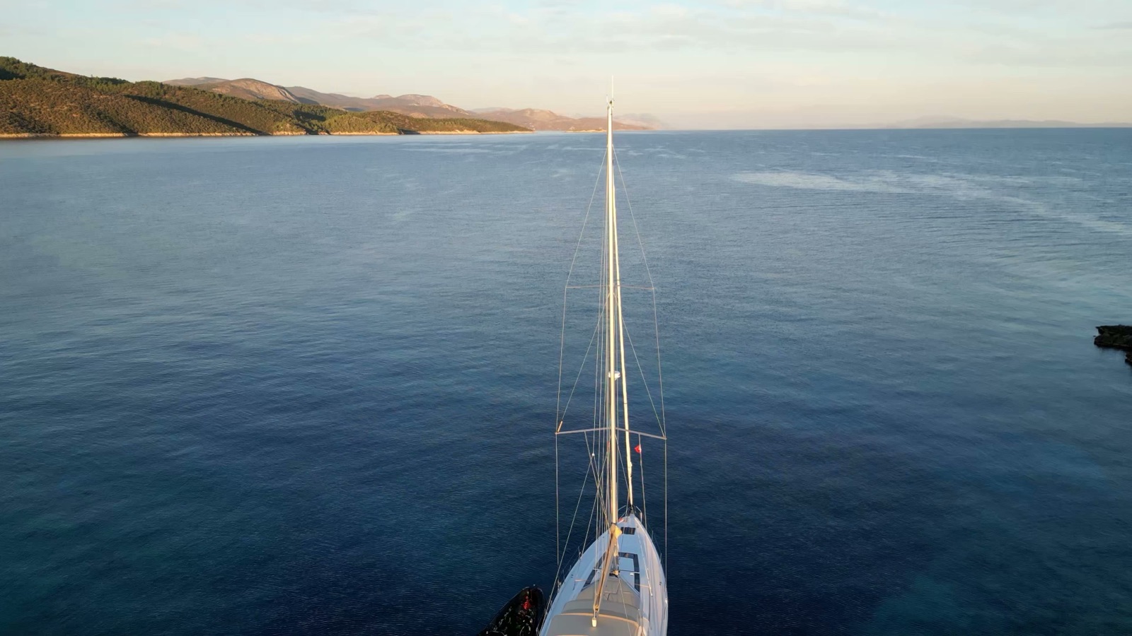 The bow of the Oceanis over open water, the peninsula low on the horizon