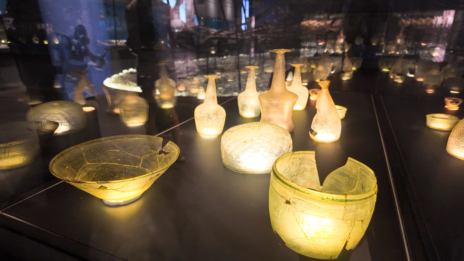Ancient glass vessels glowing in the dark glass hall